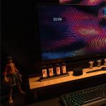 Moderne wissenschaftliche Dekoration mit LED-Lichtern, die auf einem Holzregal vor einem digitalen Bildschirm mit bunten, dynamischen Mustern präsentiert wird.