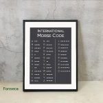 Dekoratives Morsecode-Poster mit internationalen Zeichen, ideal für Wissenschafts- und Dekorationszwecke, in einem schwarzen Rahmen an einer Betonwand.