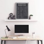 Stilvoller Arbeitsplatz mit Morse-Code-Poster, Computer, Schreibtischlampe und Pflanzen für ein inspirierendes Arbeitsumfeld.