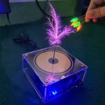 Interaktiver Plasmastrahl mit leuchtenden LED-Glühbirnen, der in einem transparenten Gehäuse schwebt und durch elektrische Felder leuchtet.