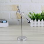 Moderne metallische Himmelskörper-Dekoration, ideal für wissenschaftliche oder dekorative Zwecke, auf hellem Holzschreibtisch mit Pflanzen im Hintergrund.