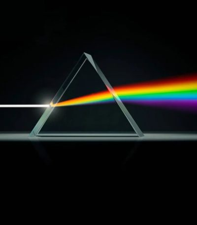Ein Prisma, das Licht in einem dunklen Hintergrund bricht, zeigt einen Regenbogen-Effekt durch Lichtbrechung.