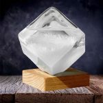 Eleganter Eiswürfel aus Glas auf Holzsockel, ideal für Dekoration und wissenschaftliche Präsentationen.