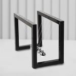 Magnetische Newton-Wiege mit zwei schwarzen Rahmen und Metallkugeln, die die physikalischen Prinzipien der Bewegung und Energieübertragung demonstrieren.