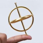 Goldenes Planetenmodell aus Metall, das auf einem Finger balanciert wird, symbolisiert das Sonnensystem und die Astronomie.
