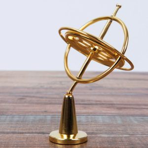 Goldfarbenes Armillarskop-Modell aus Metall auf Holzoberfläche, zeigt die Planetenbewegung und Himmelskörper in der Astronomie.