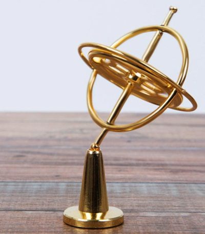 Goldfarbenes Armillarskop-Modell aus Metall auf Holzoberfläche, zeigt die Planetenbewegung und Himmelskörper in der Astronomie.
