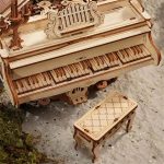 Miniatura de piano en madera con banco decorativo, ideal para decoración científica y educativa, con detalles finos y diseño clásico en madera clara.