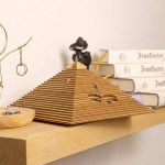 Dekorative Holzpyramide in Form einer wissenschaftlichen Struktur, auf einem Holzregal neben Büchern und wissenschaftlichen Accessoires.