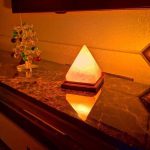 Helles Lichtobjekt in Pyramidenform auf Marmorplatte, ideal als dekoratives Element oder Nachtlicht, schafft eine warme Atmosphäre im Raum.