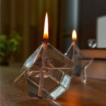 Zwei Kerzen in einem transparenten Glaswürfel, die Flammen leuchten warm und schaffen eine gemütliche Atmosphäre.