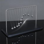 Newton-Wiege mit Metallkugeln auf schwarzem Sockel, ideal für wissenschaftliche Dekorationen und Lernzwecke.