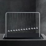 Ein metallisches harmonisches Pendel mit mehreren Kugeln, das auf einer schwarzen Basis steht, ideal für wissenschaftliche Demonstrationen und Dekorationen.