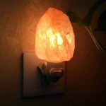 Salzlampe, die an eine Steckdose angeschlossen ist, sorgt für warmes, beruhigendes Licht in einem Raum. Perfekt für eine entspannte Atmosphäre und dekoratives Element.