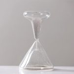 Elegante Sanduhr aus Glas mit feinem Sand, symbolisiert Zeit und Vergänglichkeit, ideal als Dekoration oder wissenschaftliches Accessoire.
