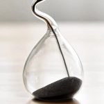 Elegantes Reagenzglas mit schwarzem Sand und Metallstab, ideal für wissenschaftliche Dekorationen und Experimente.