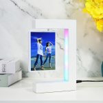 Moderner digitaler Bilderrahmen mit einem Foto von zwei Frauen am Strand, umgeben von einem weißen Rahmen mit LED-Beleuchtung, auf einem weißen Tisch.
