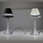 Zwei stilvolle Tischlampen mit silbernem Sockel und unterschiedlichen Lampenschirmen, eine schwarz, die andere weiß, auf einem weißen Tisch.