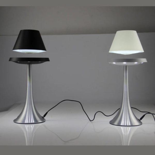Zwei stilvolle Tischlampen mit silbernem Sockel und unterschiedlichen Lampenschirmen, eine schwarz, die andere weiß, auf einem weißen Tisch.