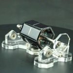 Detailliertes Modell eines Satelliten mit transparentem Gehäuse und Solarpanel, auf einer schwarzen Oberfläche.