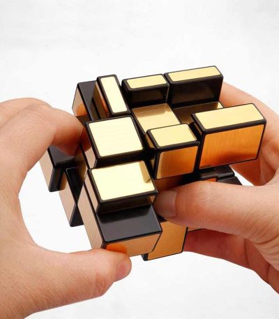 Hand hält einen komplexen, mehrfarbigen Rätselwürfel, der zum Lösen und Spielen gedacht ist, mit einem weißen Hintergrund.