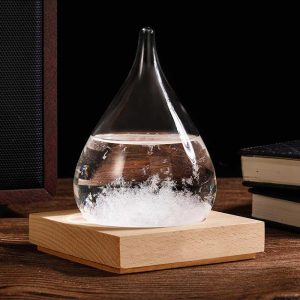 Ein Glas mit einer chemischen Reaktion, die Blasen und Schaum erzeugt, steht auf einem Holzsockel. Das Bild zeigt ein wissenschaftliches Experiment oder Dekorationsobjekt.