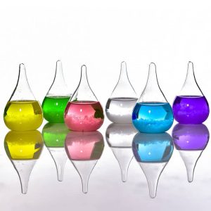 Sechs bunte chemische Reagenzgläser mit unterschiedlichen Flüssigkeiten, reflektiert auf einer glatten Oberfläche, symbolisieren Wissenschaft und Forschung.