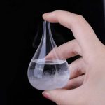 Hand hält eine kleine, transparente Glasflasche mit Dampf und Wasser, ideal als wissenschaftliches Dekorationsstück oder Lehrmaterial.