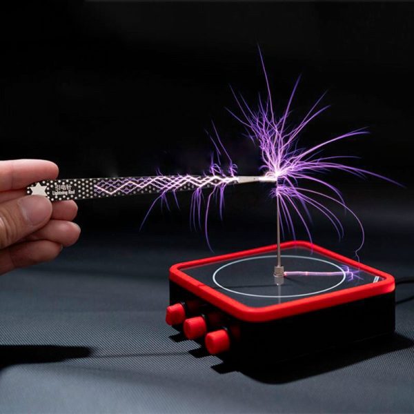 Wissenschaftliches Experiment mit Tesla-Spule, die elektrische Entladungen erzeugt, auf einem schwarzen Hintergrund.