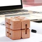 Mehrere Holz-Puzzlewürfel, die ineinander gesteckt sind, auf einem weißen Tisch mit Laptop im Hintergrund, ideal für wissenschaftliche Dekorationen und Denksport.