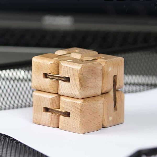 Holz-Puzzle-Objekt mit verschlungenen Teilen, das auf einer weißen Oberfläche liegt, vor einem dunklen Hintergrund.