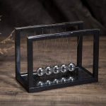 Metallisches Schwerkraftpendel in einem schwarzen Rahmen, ideal für wissenschaftliche Dekorationen und Experimente.