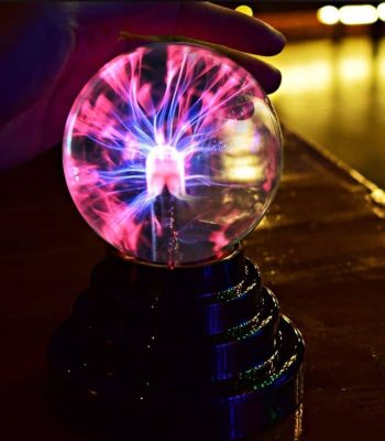 Eine Blitzkugel mit leuchtendem Plasma-Effekt, die von einer Hand gehalten wird, zeigt beeindruckende elektrische Entladungen in einem dunklen Raum.