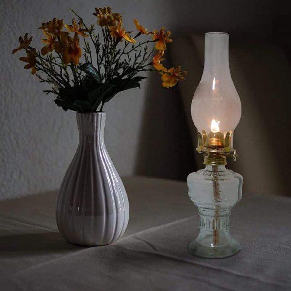 Antike Öllampe mit leuchtender Flamme neben einer Vase mit gelben Blumen, stilvolle Dekoration.