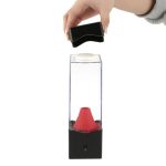 Wissenschaftliches Experiment mit Vakuum- und Drucktest, bei dem eine Hand eine Platte auf eine transparente Box mit rotem Trichter setzt.