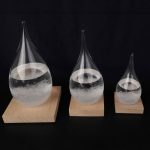 Drei Glasampullen mit Wasser auf Holzbasen, die unterschiedliche Größen haben, zeigen ein wissenschaftliches Experiment zur Wasserreflexion und -brechung.