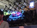 Holographisches Auto in leuchtenden Farben, projiziert auf eine transparente Oberfläche, umgeben von digitalem Datenfluss, auf einer Wissenschaftsmesse.