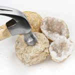 Stein mit Geode und Hammer, Nahaufnahme, wissenschaftliches Dekor, Naturmaterialien, Mineralien, Kristalle, Mineralienforschung, Dekorationsobjekt, wissenschaftliches Zubehör, Geologie, Mineralienanal.