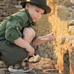 Junge Archäologin untersucht antike Steine mit Lupe und Werkzeug, um historische Artefakte zu entdecken. Perfekt für Wissenschafts- und Geschichtsliebhaber.