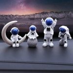 Vier Astronautenfiguren in Weltraumanzügen mit Helm, auf Mondlandschaft mit Bergkette und Sternenhimmel im Hintergrund. Perfekt für wissenschaftliche Dekorationen und Raumfahrt-Themen.