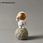 Kreative Astronautenfigur mit goldenem Helm, die auf einem Mondgestein steht. Perfekt als Dekoration für Wissenschafts- und Raumfahrtliebhaber.