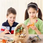 Kinder spielen mit Dinosaurier-Figuren in einem großen, aufgebrochenen Eierschale, die als kreative Spiel- und Dekorationsidee dient. Perfekt für Wissenschafts- und Dinosaurierliebhaber.