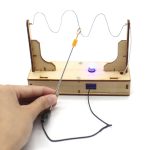Wissenschaftliches Experiment mit Spule, LED und Holzrahmen, zeigt elektromagnetische Induktion in einem DIY-Labor-Setup.