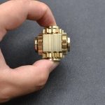 Hand hält ein komplexes, goldenes wissenschaftliches Modell mit mechanischen Komponenten, ideal für Dekoration und Bildung.