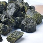 Natürliche schwarze Steine mit grünen Flecken, ideal für wissenschaftliche und dekorative Zwecke.