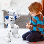 Ein kleiner Junge spielt mit einem weißen und blauen Roboter, der auf dem Boden sitzt. Das Bild zeigt die Interaktion zwischen Kind und Technologie in einem hellen, modernen Raum.