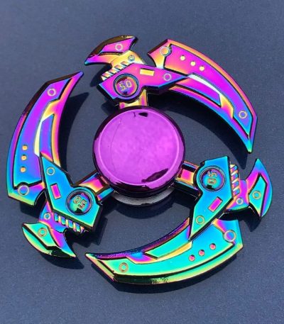 Buntes Schwerkraft-Spielzeug aus Metall mit holographischem Finish, das in einer kreisförmigen Anordnung auf dunklem Hintergrund liegt.