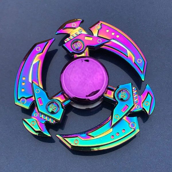 Buntes Schwerkraft-Spielzeug aus Metall mit holographischem Finish, das in einer kreisförmigen Anordnung auf dunklem Hintergrund liegt.