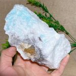 Hand hält einen großen, bläulich schimmernden Kristallstein mit weißen und grauen Flecken, ideal für wissenschaftliche Dekorationen und Sammlerstücke.