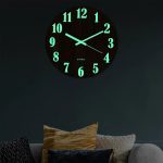 Leuchtende Wanduhr mit fluoreszierenden Ziffern und Zeigern, ideal für dunkle Räume und moderne Inneneinrichtung.